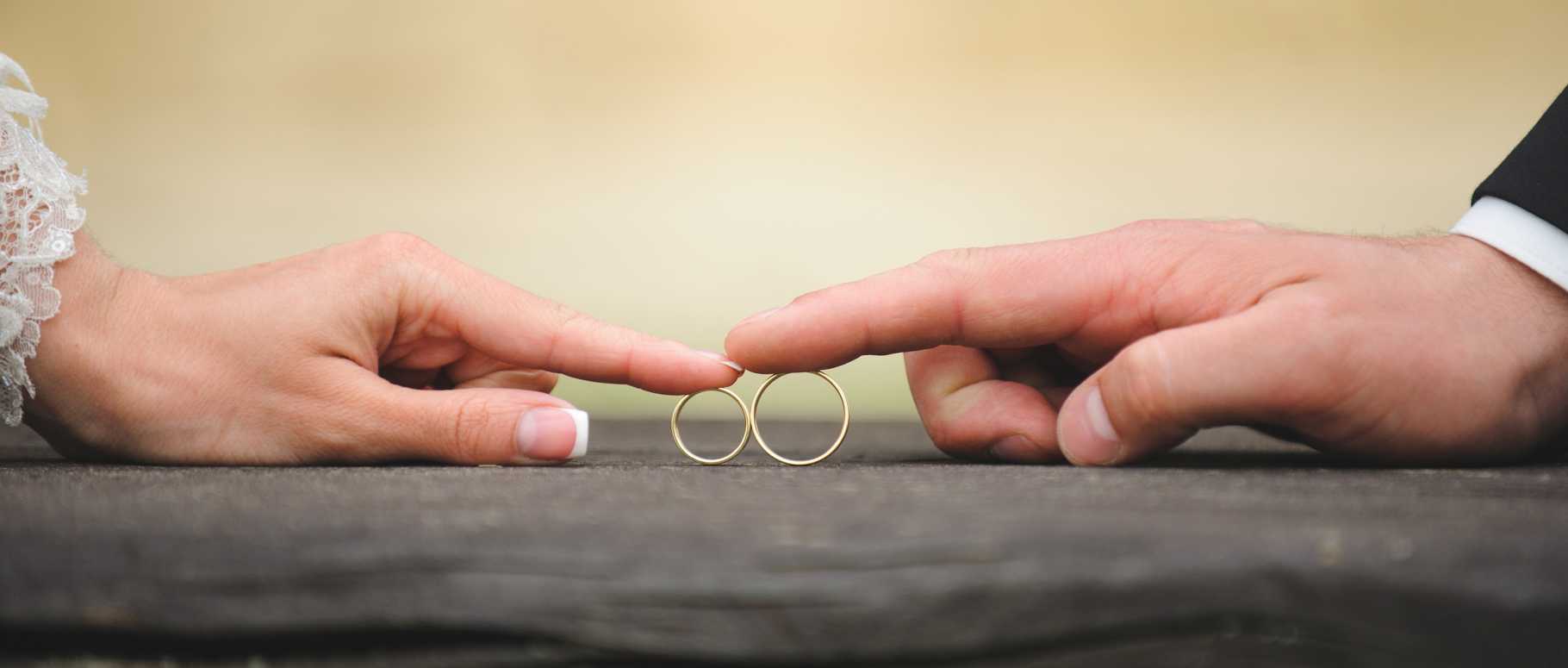 bride and groom touching rings by finger